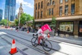 Foodora bicycle rider doing food delivery in downtown of Sydney near the QVB building.